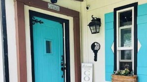 A cottage entrance with a turquoise door, a 'Welcome to Cottage' sign, a lantern, and a window with shutters. - Cozy, 1 bedroom Cottage with Mountain views! (Tolleson)