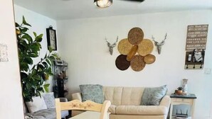 A dining area with a wooden table and chairs, a sofa, and a ceiling fan. - Cozy, 1 bedroom Cottage with Mountain views! (Tolleson)