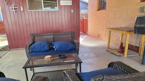 A red exterior wall with a 'Laundry' sign, wicker furniture, and a small table with a bowl.