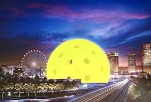 A cityscape with a large yellow moon-like object superimposed over the scene. - Middle of VEGAS CES EDC SPHERE, on GRAND PRIX track 2b2b Suites walk to Strip (Las Vegas)