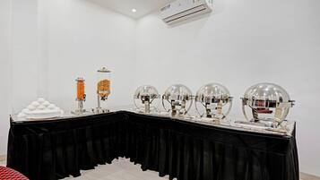 A room with a long table covered by a black cloth, featuring a water dispenser, a food dispenser, and four spherical objects.