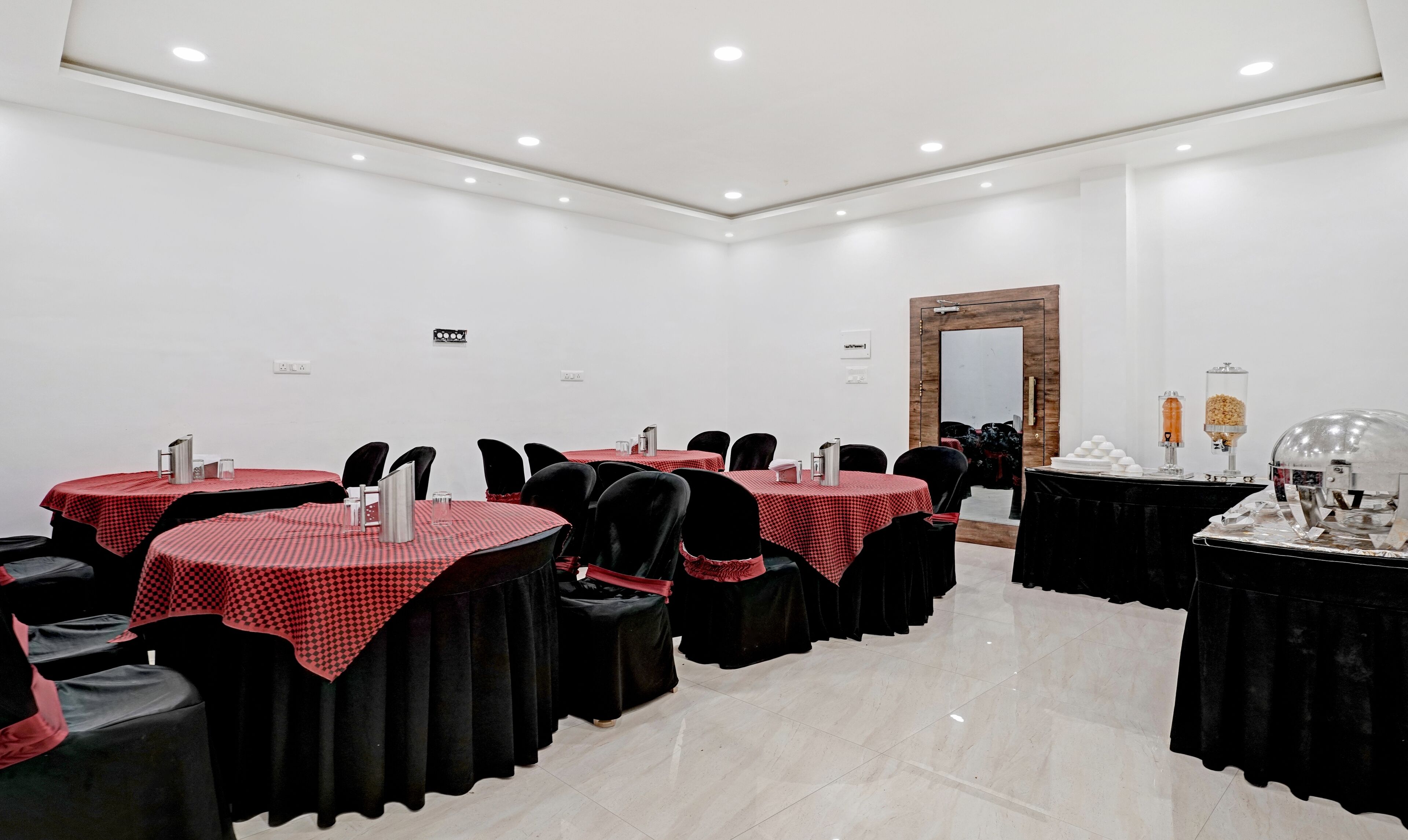 Un salón de conferencias con varias mesas, sillas y un espejo grande.