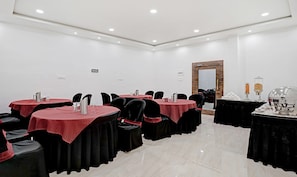 A conference room with multiple tables, chairs, and a large mirror.