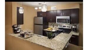 A modern kitchen with granite countertops, stainless steel appliances, and dark wooden cabinets. - In The Center Of It All, Right Next To The Sphere, Ten Minute Walk To The Strip (Las Vegas)
