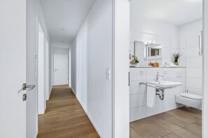 Une salle de bain moderne avec un lavabo blanc, un miroir et des toilettes.