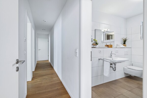 A modern bathroom with a white sink, a mirror, and a toilet.