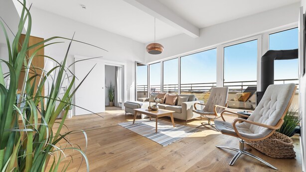 A spacious living area with a large window, a sofa, a chair, and a coffee table.