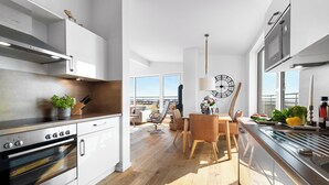 A modern kitchen with stainless steel appliances, wooden flooring, and a dining area with a view.