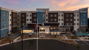 A multi-story hotel with a central entrance, a flag, and a pool area. - Residence Inn By Marriott Fresno Clovis (Clovis)
