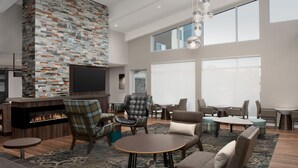 A spacious lounge area with a fireplace, comfortable seating, and large windows providing natural light. - Residence Inn By Marriott Fresno Clovis (Clovis)