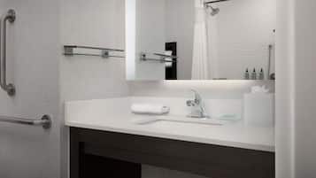 A modern bathroom with a white sink, a mirror, a towel rack, and a shower curtain.