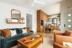 A modern living room with a sofa, coffee table, and a dining area with chairs.