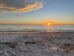 A beach with a sunset over the ocean.