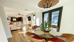 Un coin repas avec des chaises en osier, une table en verre et un ventilateur de plafond.