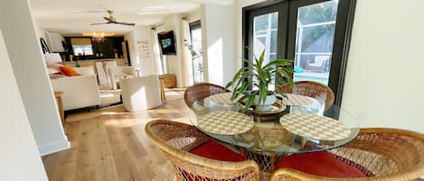 A dining area with wicker chairs, a glass table, and a ceiling fan.