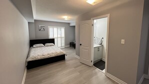 A bedroom with a bed, a door to a bathroom, and a ceiling light.