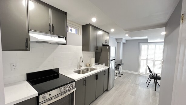 A modern kitchen with dark cabinets, a black stove, and a white countertop.
