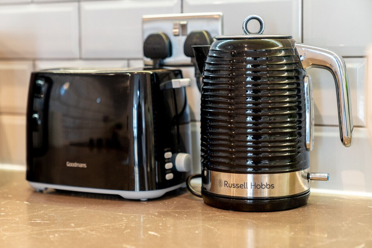 Una cocina con una tostadora negra y una cafetera negra con base metálica.