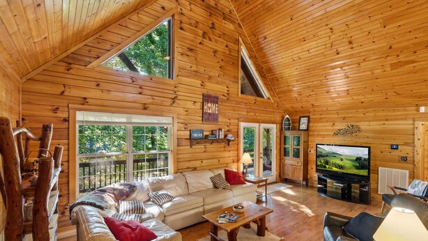 A log cabin interior with a large sofa, a television, and a fireplace. - Spacious Retreat on Dale Hollow! Walking distance to Safe Harbor Wisdom Dock. (Albany)