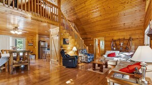 A spacious wooden interior with a staircase, a sofa, a chair, and a dining table. - Spacious Retreat on Dale Hollow! Walking distance to Safe Harbor Wisdom Dock. (Albany)