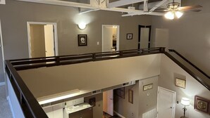 A multi-level interior with a staircase, a ceiling fan, and a view of the lower level. - Historic High School Loft 4 min drive from Oaklawn! (Hot Springs)