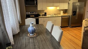 A modern kitchen with a dining table, chairs, a microwave, stove, refrigerator, and cabinets. - Historic High School Loft 4 min drive from Oaklawn! (Hot Springs)
