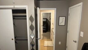 A bedroom with a bed, a closet, and a hallway leading to a bathroom. - Historic High School Loft 4 min drive from Oaklawn! (Hot Springs)