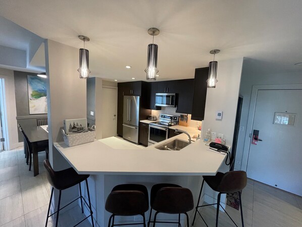 A modern kitchen with a central island, stainless steel appliances, and pendant lighting.