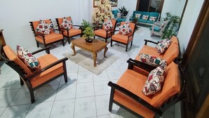 Een woonkamer met oranje banken en fauteuils, een houten salontafel en een kerstboom.