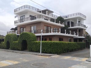 A multi-story residential building with balconies, a brick facade, and a well-maintained hedge. - Starfish Hotel (Puerto Villamil)