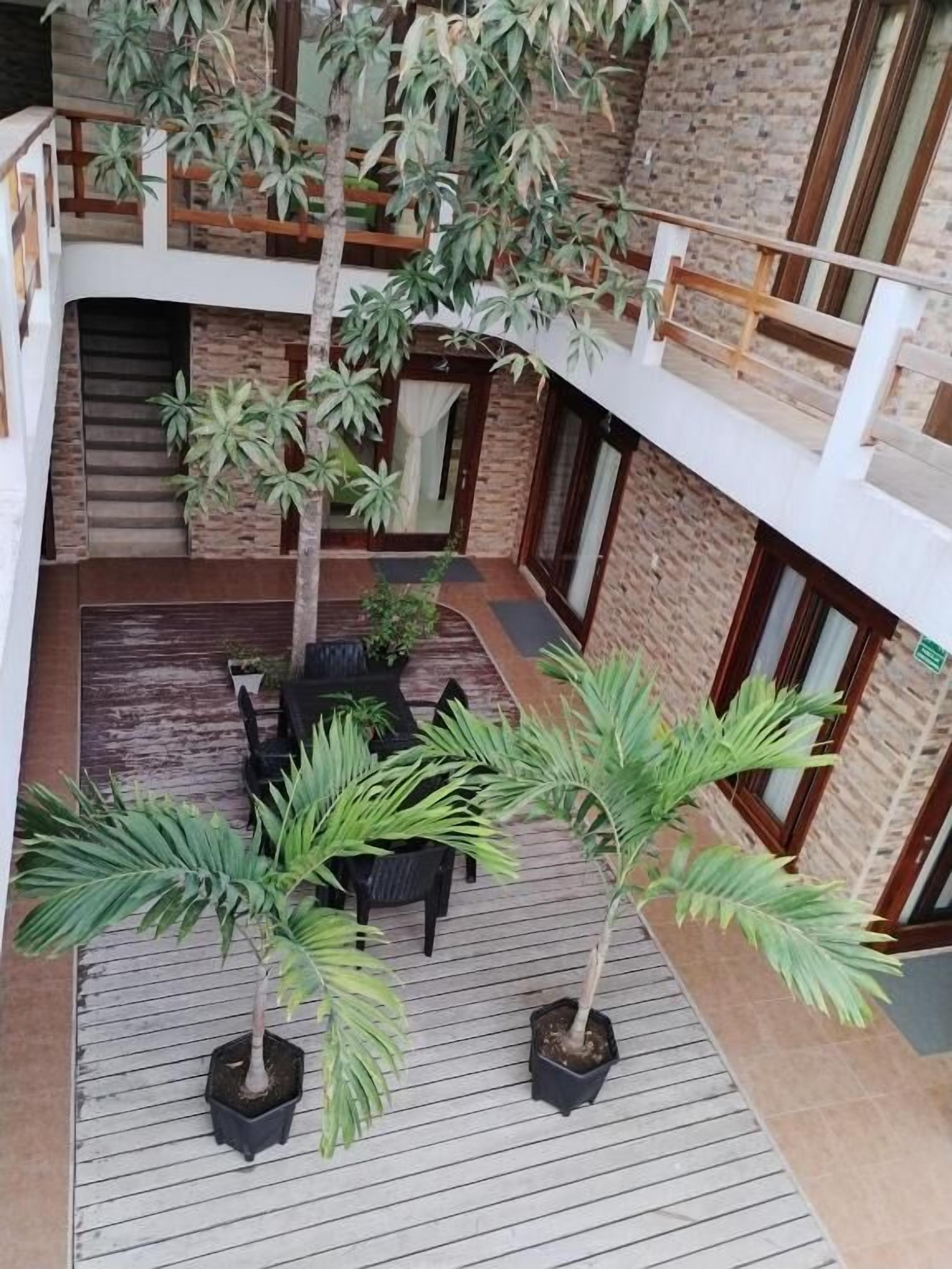 A multi-level outdoor area with potted plants, wooden flooring, and a brick wall.