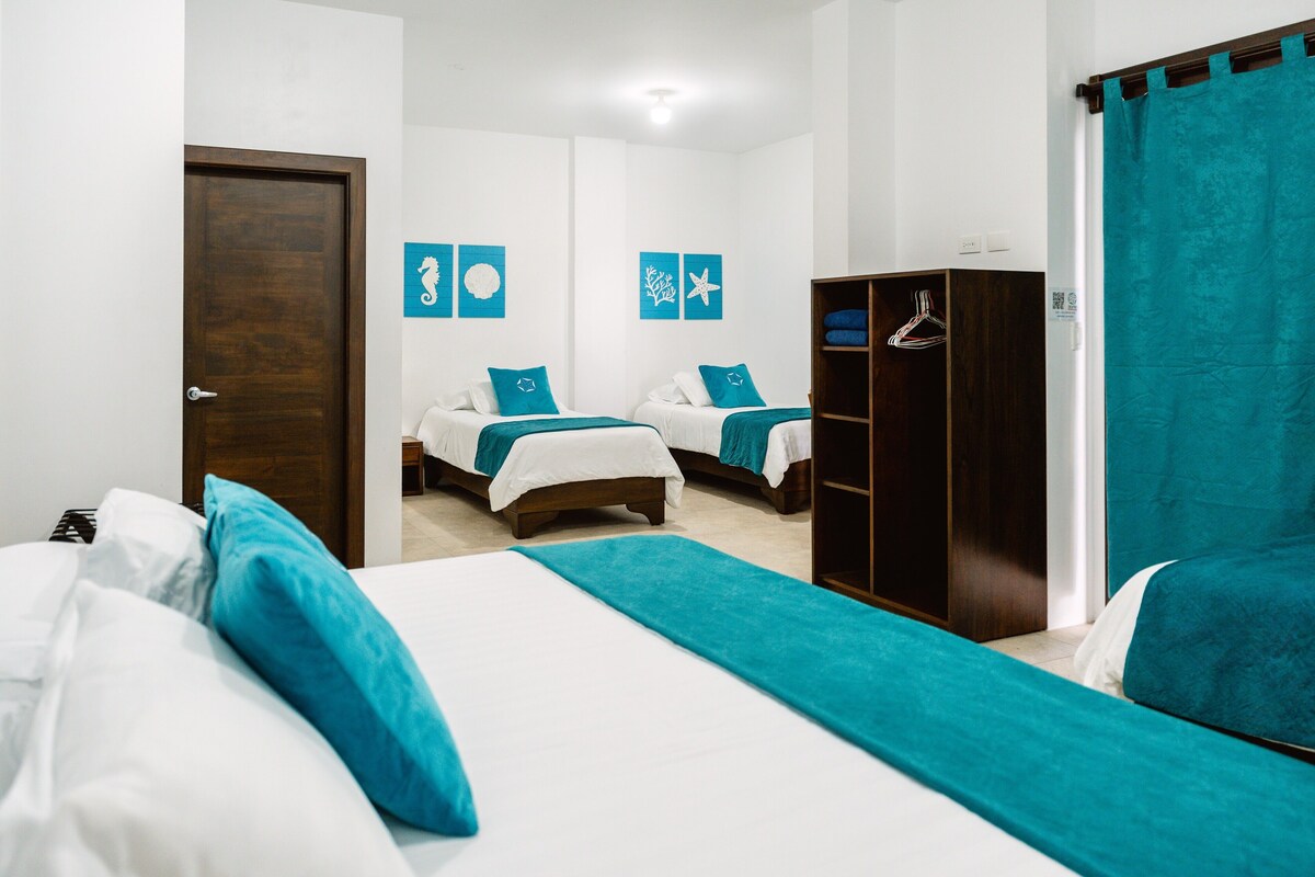 A hotel room with two beds, a wardrobe, and a door.