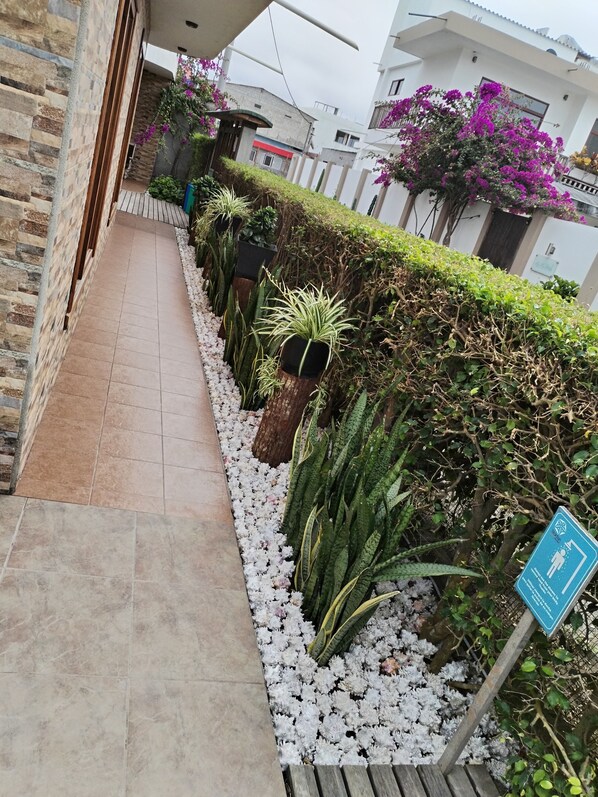 A pathway lined with potted plants and a sign indicating a wheelchair-accessible area. - Starfish Hotel (Puerto Villamil)