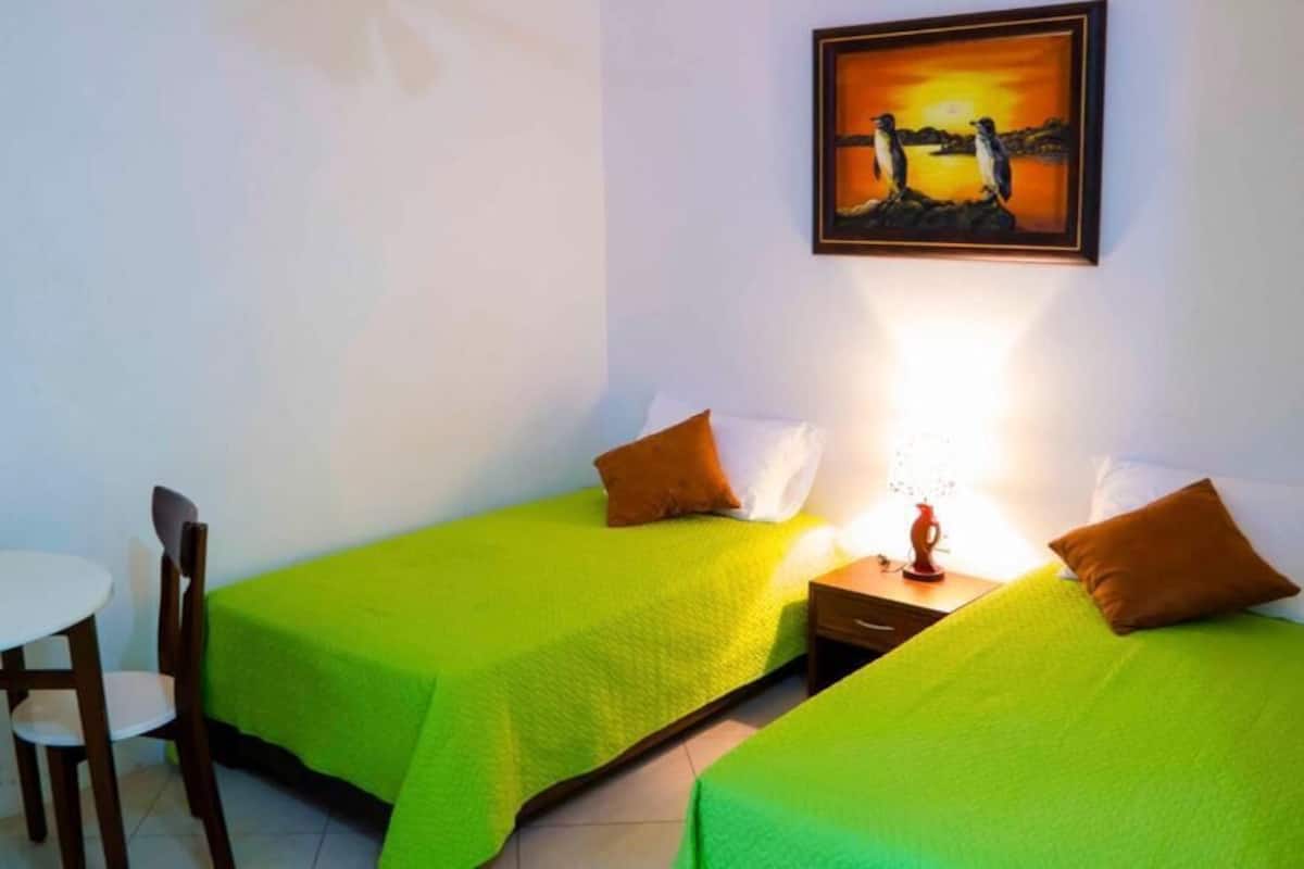 A room with two beds, a small table, and a chair.
