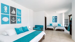 Een hotelkamer met een groot bed, twee kleinere bedden, een stoel en uitzicht op zee.