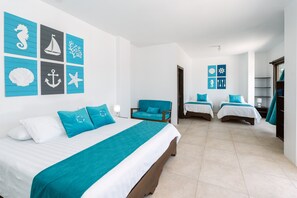 A hotel room with a large bed, two smaller beds, a chair, and a view of the sea. - Starfish Hotel (Puerto Villamil)