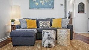 Una sala de estar con un sofá gris, cojines estampados y dos mesitas redondas con diseños de mosaico.