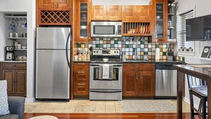 Una cocina moderna con electrodomésticos de acero inoxidable, armarios de madera y salpicadero de azulejos.