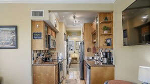 A compact kitchen with wooden cabinets, a built-in stove, and a coffee maker.