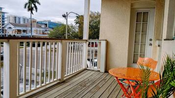 A wooden deck with a white railing, a table with chairs, and a door.