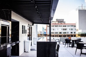 A rooftop terrace with a black marble bar, outdoor seating, and a view of the cityscape. - Apart no Maradisa Design por Carpediem (João Pessoa)