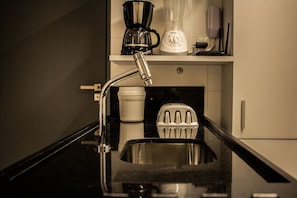 Une cuisine équipée d’un évier en acier inoxydable, d’une machine à café, d’un mixeur et d’une centrifugeuse, le tout posé sur le plan de travail.