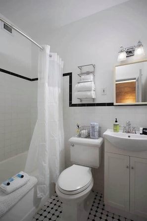 Bathtub, hair dryer, towels, shampoo