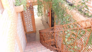 A staircase with a wrought iron railing, brick walls, and potted plants. - Vista Del Sol Apartments (San Miguel de Allende)