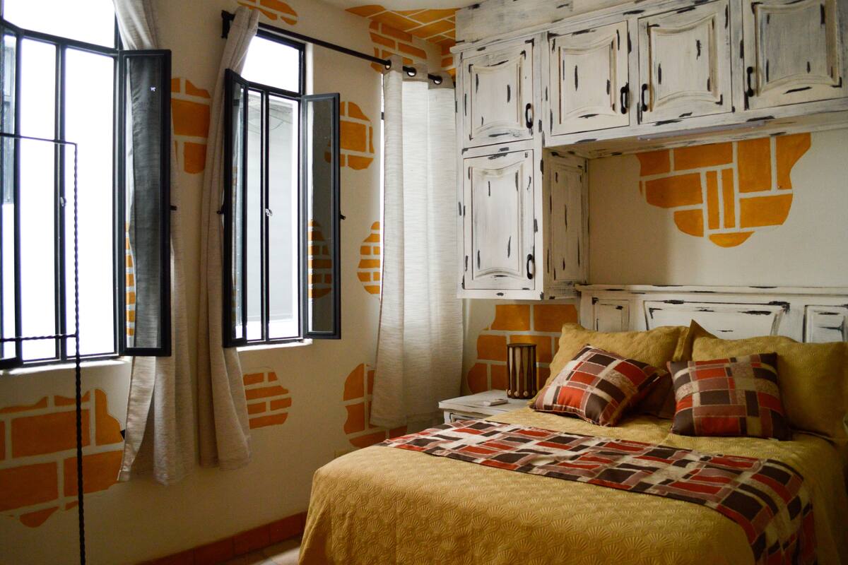 Une chambre à coucher avec un lit, des rideaux et une fenêtre donnant sur l’extérieur.