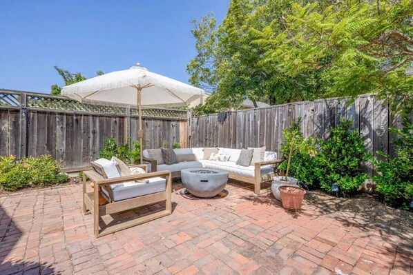 Relax in a serene, outdoor space with a fire pit, bench, and umbrella.