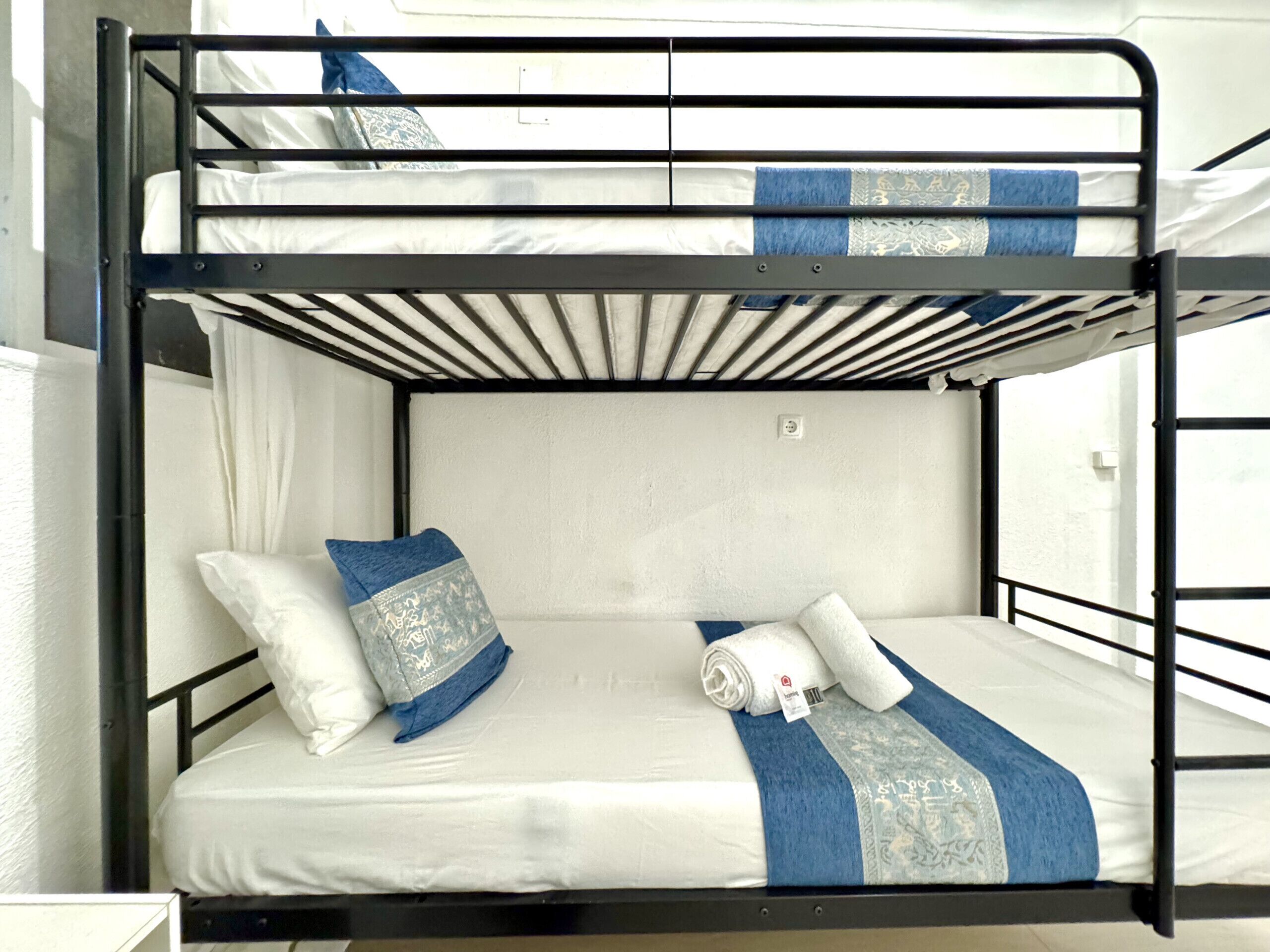 A bunk bed with white bedding and blue accents, including pillows and a blanket.