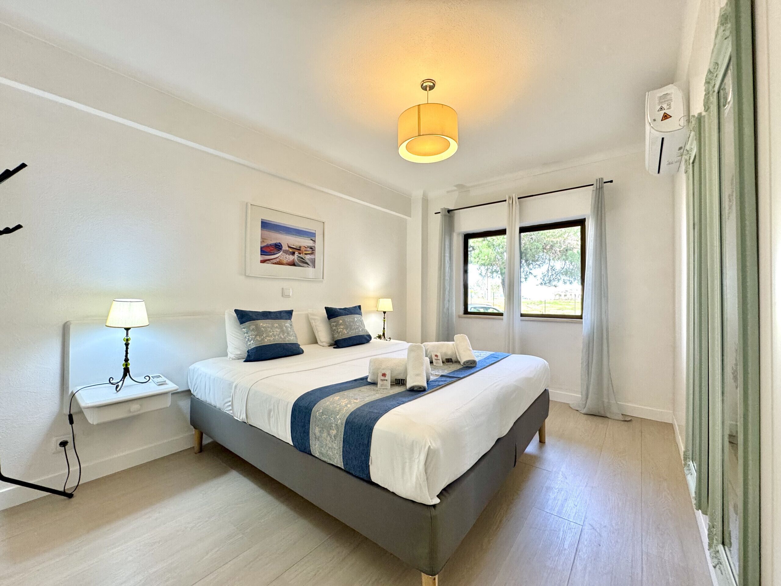 A modern hotel room with a large bed, bedside tables, a ceiling light, and a window with curtains.