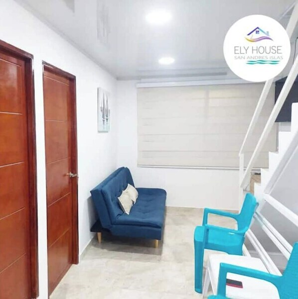 Une pièce avec un canapé bleu, une petite table et un escalier.