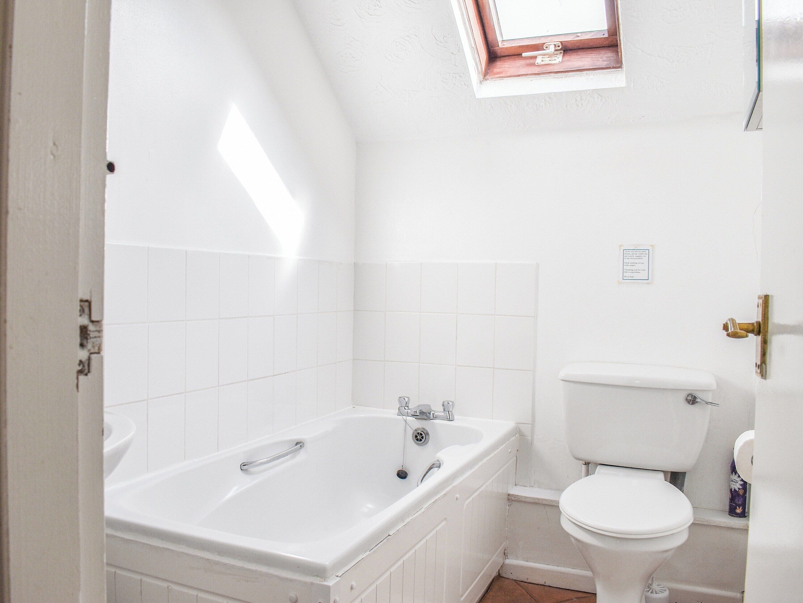 Une salle de bain avec une baignoire, des toilettes et une petite fenêtre.